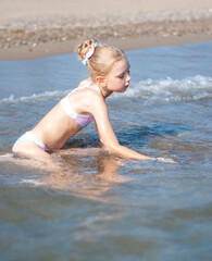 little girl playing on the beach by the sea
