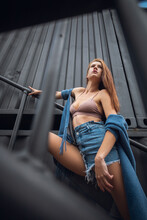 Creative Portrait Of A Red-haired Woman In A Short  Shorts And Top. Design Concept. Romantic Portrait Of Young Woman Posing In Urban Area