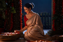 Woman Decorating Entrance By Placing Floating Diyas On The Occasion Of Diwali