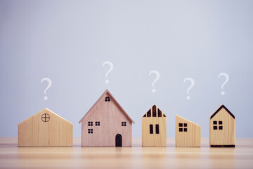 Difference house model with question marks on table background, planning to buy property, loan concept