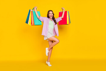 Sticker - Full length body size photo careless woman jumping up keeping shopping packages isolated bright yellow color background