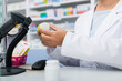 cropped view of pharmacist in white coat scanning bottle with medication at counter
