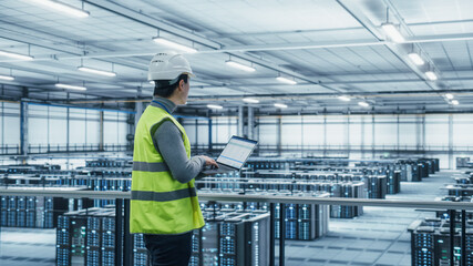 Poster - Data Center Engineer in High Visibility Vest Using Laptop Computer. Server Farm Cloud Computing Facility with Asian Male System Administrator Working with Data Protection Network for Cyber Security.