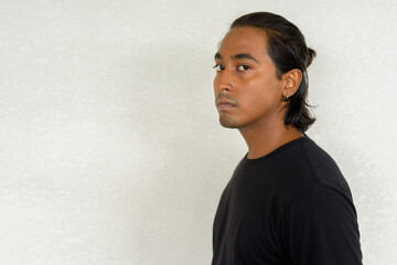 Profile view portrait of handsome young Indian man against plain background