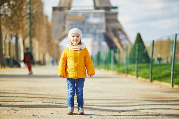 Wall Mural - Adorable toddler girl walking near the Eiffel tower in Paris, France