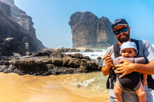 A Young Father With His Baby In The Roque Del Moro Of The Cofete Beach Of The Natural Park Of Jandia, Barlovento, South Of Fuerteventura, Canary Islands. Spain
