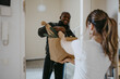 © Maskot - Smiling man giving paper bag of groceries to woman standing at doorway