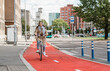 © Syda Productions - traffic, city transport and people concept - happy smiling woman riding bicycle along red bike lane or two way road on street