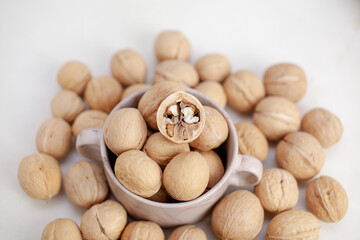 Aufkleber - A lot of whole walnuts in a cup on a white background close-up. Healthy, organic food with a high content of protein and protein.
