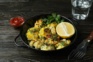 Concept of tasty food with baked cauliflower on wooden background