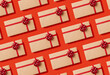 © maicasaa - Seamless pattern of holiday gift boxes wrapped in craft paper with a red bow on red background. Top view.