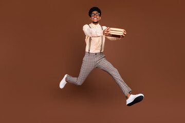 Wall Mural - Photo of nerd book worm guy jump run carry pile materials wear suspenders shoes isolated brown color background