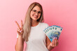 © Asier - Young russian woman holding bills isolated on pink background showing number two with fingers.