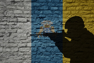 Wall Mural - Soldier silhouette on the old brick wall with flag of canary islands country.