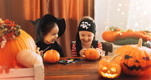 Children In Costumes Paint Faces On Pumpkins