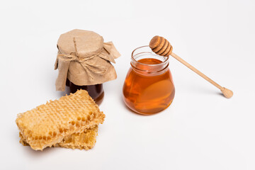 Poster - jars with yellow and brown honey near wooden dipper and honeycomb on white