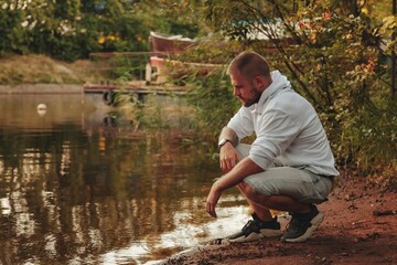 Wall Mural - Portrait of young bearded man with tattoos in white jacket in countryside