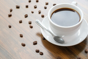 Poster - White cup of coffee on a wooden table with coffee beans