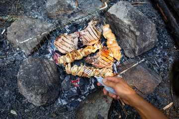 Top view of a man grilling juicy meat on coal