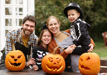 Young Caucasian Family Mother Father And Children In Halloween Costumes At Decorated Backyard