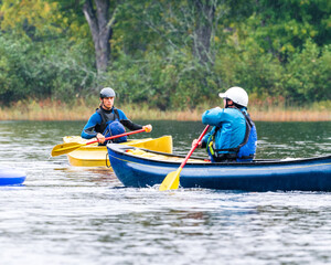 two canoeists practice paddle strokes on a rainy fall day during a “moving water” paddling course. a