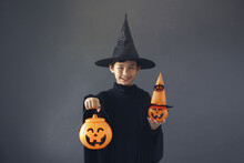 Cute Asian Boy Celebrating Halloween By Wearing Witch Costume And Holding Halloween Decoration Accessories