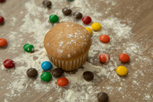 Baked Muffin With Various Colored Chocolates, Dusted With Sugar, Delicious Desserts With Details In The Texture