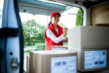 Portrait of hardworking female courier arranging packages before delivery.