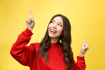 Wall Mural - Young beautiful asian woman pointing to copyspace, isolated on yellow background