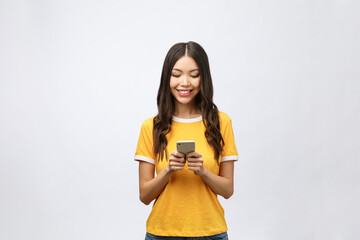 Wall Mural - Attractive Asian teenage girl looking at her mobile phone screen with joyful face, on white background for copy space.