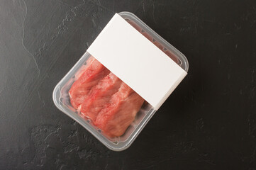 perfect raw tenderloin in plastic packaging on a black background. top view. logo design.