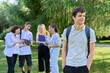 Portrait of male student in park campus, group of teenagers with teacher background