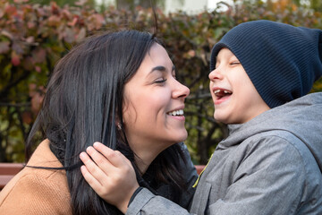 Young mom with her son hug on the bench.