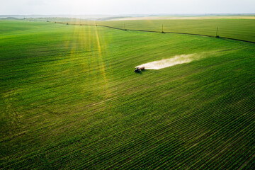 Poster - Scenic top view of a tractor spraying green fields.