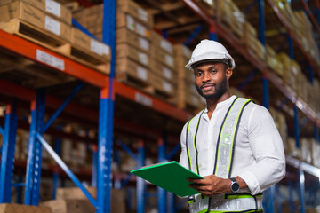 Wall Mural - Portrait of an African warehouse manager holding a clipboard checking inventory in a large distribution center.