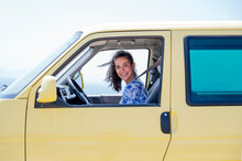 Happy Mid Adult Woman Sitting In Yellow Camper Van During Sunny Day