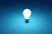 Three Dimensional Render Of Single Light Bulb Glowing Against Blue Background