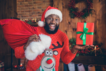 Poster - Photo of charming impressed dark skin guy dressed print pullover smiling holding present bag indoors house home room