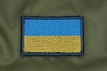 one rectangular blue yellow patch of the ukrainian flag on the green fabric of the backpack