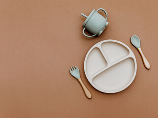 Wall Mural - Composition with baby food accessory on brown background. Neutral pastel colors