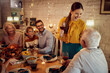 © Drazen - Happy woman holds a toast during Thanksgiving dinner with her family at home.