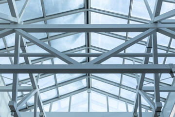 Steel frame of the glazed roof of a warehouse, shopping or office center. The ceilings are made of metal beams interconnected by welding to maintain rigidity.