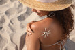 © New Africa - African American woman with sun protection cream on shoulder at sandy beach
