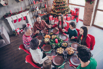 Canvas Print - Photo portrait family praying together on xmas holding hands sitting at table before dinner in apartment