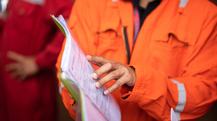 Wall Mural - Action of a supervisor pointing on document paper for discussion during a safety audit and operation commisionning. Indsutrial worker people photo. Selective focus at the people hand.