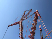 Jib Of Giant Crane Opposite Bright Blue Sky. Bottom Up View