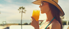 Side Profile Cropped Panoramic View Face Beautiful Woman, Wear Straw Hat Hold Glass Drinks Orange Juice Or Cocktail Refreshing At Hot Day Relax On Deckchair Near Pool. Enjoy Summer Holidays Concept