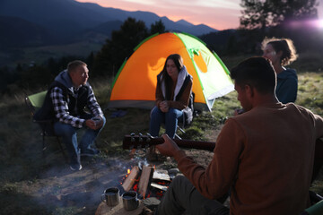 Poster - Group of friends gathering around bonfire at camping site in evening