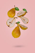 Creative food concept with fresh ripe whole and sliced pears flying in air isolated on a light pink background.