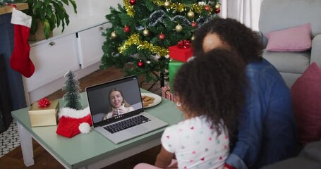 Poster - African american mother and daughter having a videocall on laptop at home during christmas